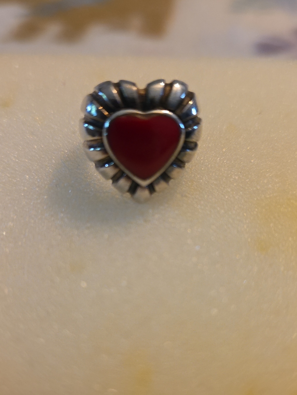 silver-toned ring featuring a small red heart center